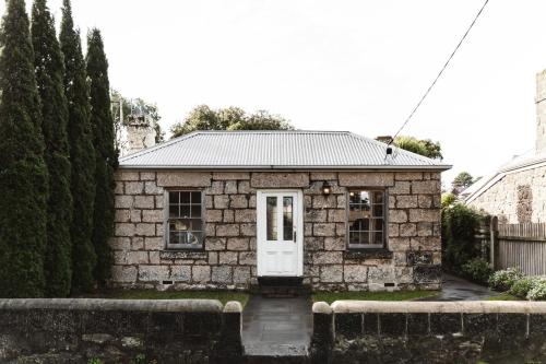 a small stone house with a white door at Historic 1850s Magnetic Cottage in Port Fairy