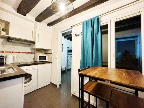 une cuisine avec des armoires blanches et une table en bois dans l'établissement StNicolas1 Frenche Style Appt Bastille, à Paris