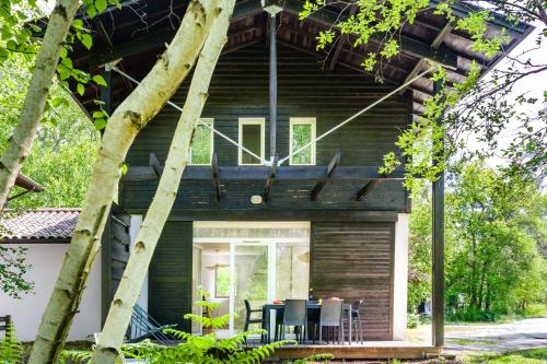 a house with a wrap around porch with tables and chairs at La Cachette du Lac Un cocon nature pour des souvenirs inoubliables in Lacanau