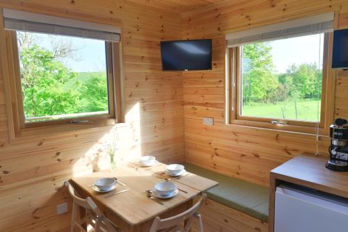 a wooden room with a wooden table and two windows at Anniston Mill Cabin 2 in Arbroath
