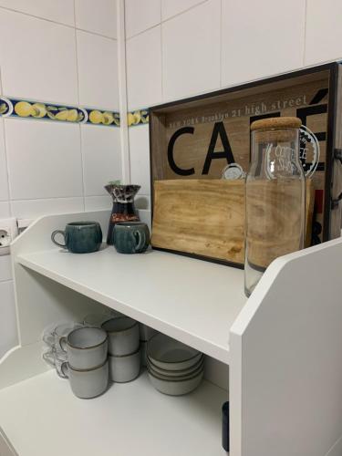 a white shelf in a kitchen with bowls and a sign at La casita de Kalani in Comillas