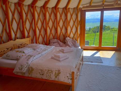 uma cama num quarto com uma grande janela em Woda Góry Las - glamping CAŁOROCZNY em Szlembark