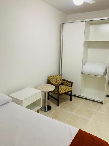 a bedroom with a bed and a chair and a table at Lagamar Hotel Varginha in Varginha