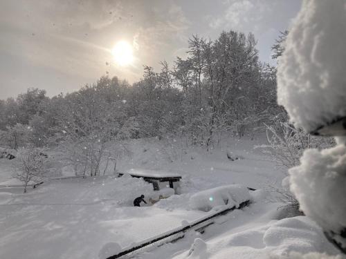 uma mesa de piquenique coberta de neve com o sol ao fundo em Minanonno Play Village em Yoichi