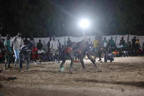 two men playing a game of frisbee at night at La Teranga Toubacouta in Bani