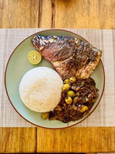 a plate of food with a piece of fish and rice at La Teranga Toubacouta in Bani