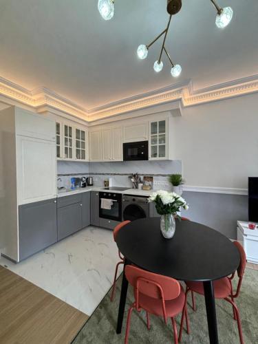 une cuisine avec une table noire et des chaises rouges dans l'établissement Superbe appartement Paris 3ème, à Paris
