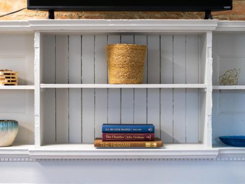 a stack of books on a shelf with a basket at Carriage Manor - Sun Soaked 1BR - Close to CCF in Cleveland