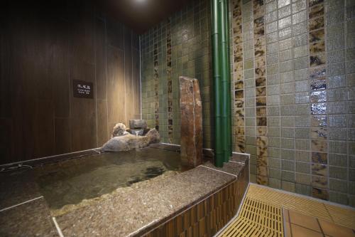 a bathroom with a large tub with a sink at Dormy Inn Maebashi in Maebashi