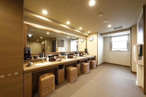 a bathroom with a row of sinks and a large mirror at Dormy Inn Maebashi in Maebashi