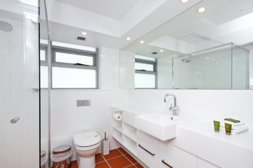 a white bathroom with a toilet and a sink at Fairshore 38 Beachfront Balcony in Noosa Heads