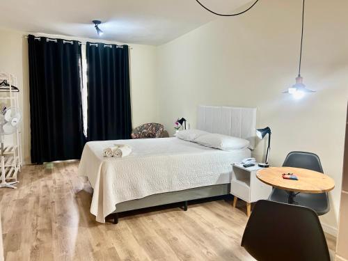 a bedroom with a bed and a table with chairs at Ap Smart Hub in Campinas