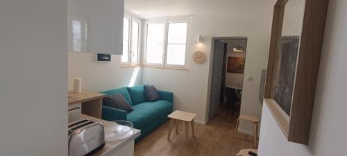un salon avec un canapé bleu et une fenêtre dans l'établissement Cassiopée-SILS - T1 28 M2, à Caen