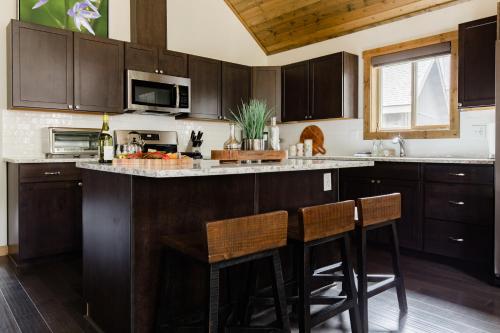 a kitchen with wooden cabinets and a island with bar stools at Pine Forest Getaway, Game Room, Hot Tub, Fire Pit in Ronald