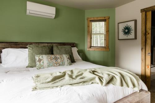 a bedroom with a white bed with green walls at Pine Forest Getaway, Game Room, Hot Tub, Fire Pit in Ronald