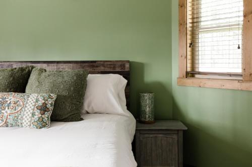 a bedroom with a bed with green walls and a window at Pine Forest Getaway, Game Room, Hot Tub, Fire Pit in Ronald