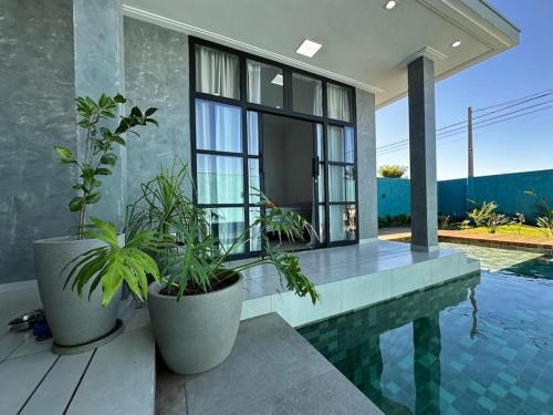 una casa con piscina e due piante in vaso di Casa Lamparina a Santa Fé do Sul
