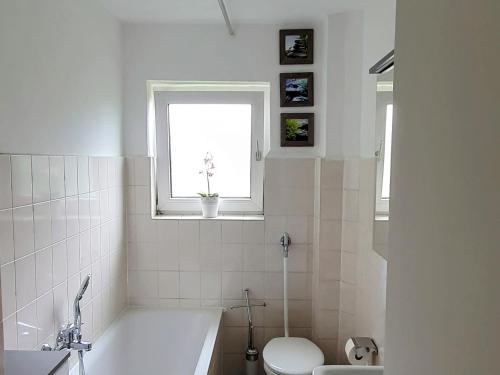 uma casa de banho com uma banheira, um WC e uma janela. em Dream Home in Dortmund em Dortmund