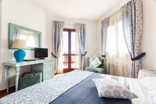 a bedroom with a bed and a desk and a television at Hotel Stefania Boutique Hotel by the Beach in Olbia