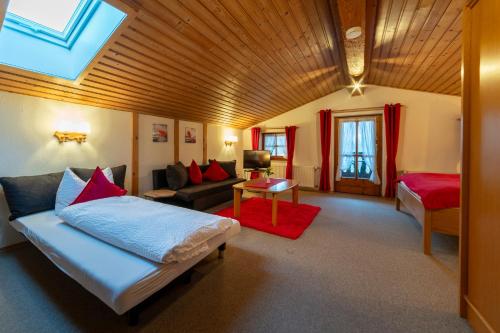 a living room with a couch and a bed in a room at Gästehaus beim Schneidersepp in Ruhpolding