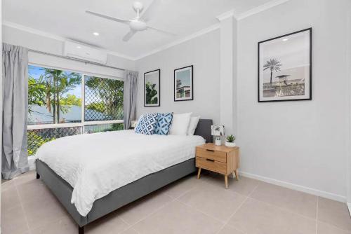 a bedroom with a bed and a large window at Belle Escapes Sandpipers Beach House in Palm Cove