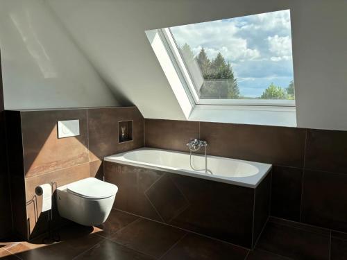 een badkamer met een toilet en een bad met een raam bij Spacious holiday home with garden in Elsenborn