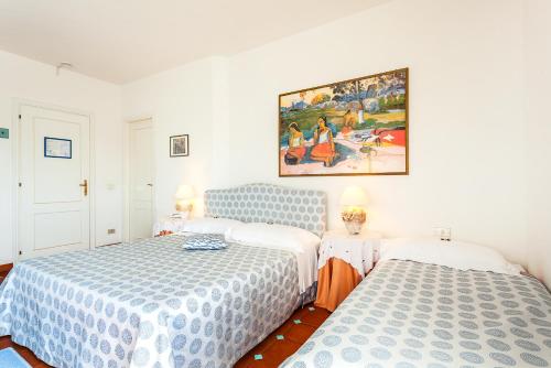 a bedroom with two beds and a painting on the wall at Hotel Stefania Boutique Hotel by the Beach in Olbia
