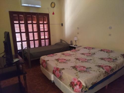 1 dormitorio con 1 cama, TV y ventana en Hostal Lo de Ramona en Belén