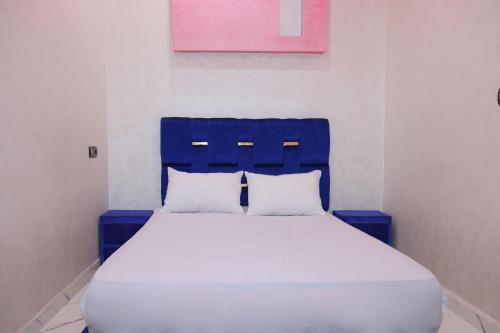 ein blaues Bett mit zwei weißen Kissen in einem Zimmer in der Unterkunft Bel appartement-Haut débit WIFI in El Aaiún