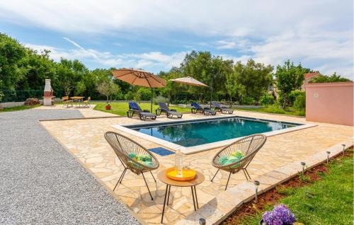 a swimming pool with two chairs and an umbrella at Beautiful Apartment In Malinska in Malinska