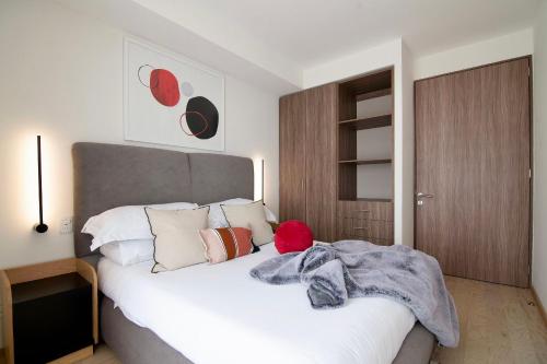 una camera da letto con un grande letto bianco con cuscini di SANTA FE Red Beautiful Apartment! a Città del Messico