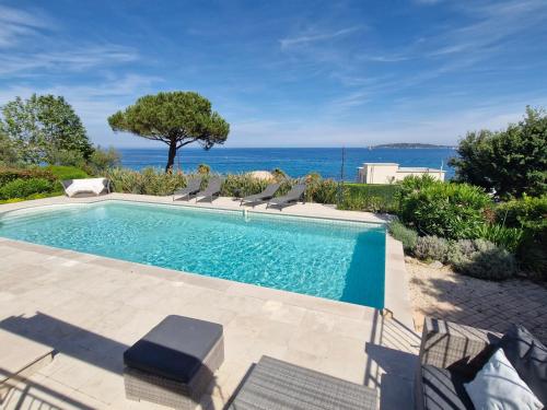 une piscine avec des chaises et l'océan en arrière-plan dans l'établissement Villa 5 pièces + T2, piscine, clim, bord de mer, 10-12 pers - FR-1-780-3, à Sainte-Maxime