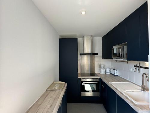 - une cuisine avec des armoires bleu foncé et un évier dans l'établissement Élégant appartement à Fouras: proche centre-ville et plage avec terrasse et balcon - FR-1-709-73, à Fouras