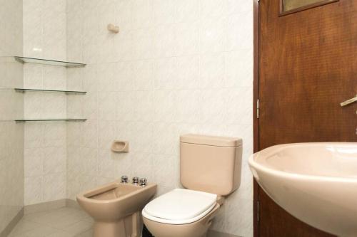 a white bathroom with a toilet and a sink at Urquiza Apart in Salta