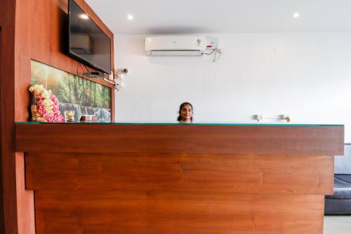 a woman standing behind a counter in a kitchen at Capital O Sai Arya Residency in Mangalore