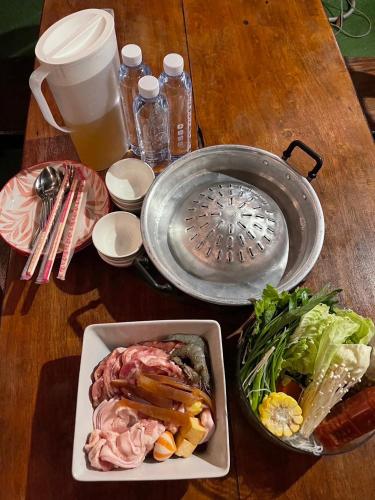 a table with a plate of food and a bowl of salad at Baan Siri in Ban Dong Bang