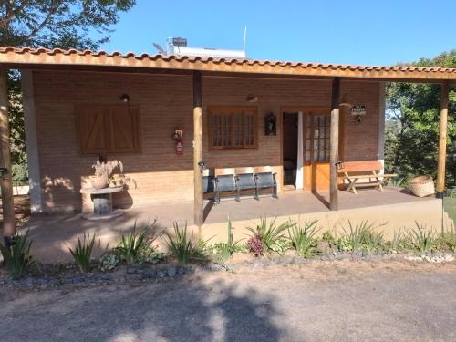a small house with a porch and a bench at Chales rota da pedra in São Bento do Sapucaí