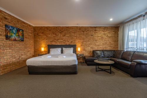 a bedroom with a bed and a leather couch at Wonthaggi Motel in Wonthaggi