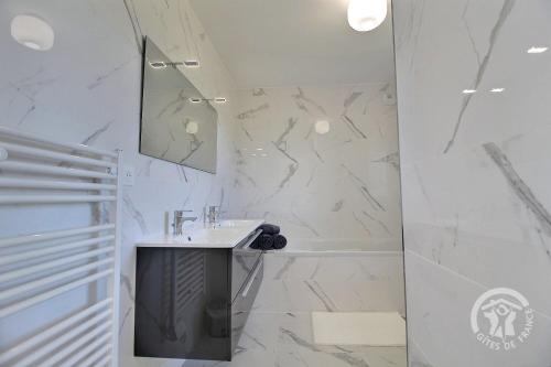 a white bathroom with a sink and a tub at Kergonet in Plougrescant