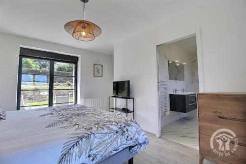 a white bedroom with a bed and a television at Kergonet in Plougrescant