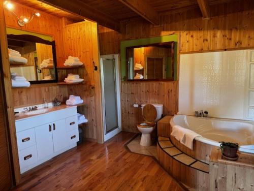 a bathroom with a tub and a toilet and a sink at Le Chadou in Tadoussac