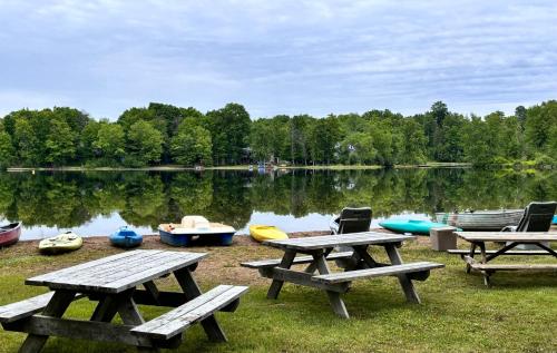 a group of picnic tables and boats on a lake at Lakefront Hideaway Resort 10 Total cabins-Lake View, Private Beach in Kawartha Lakes