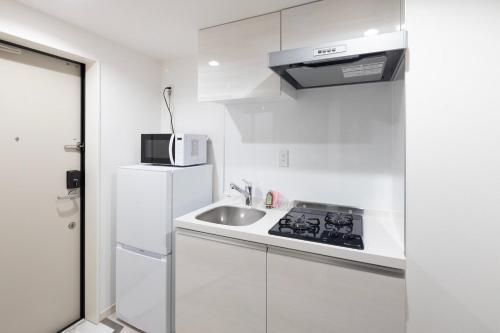a white kitchen with a sink and a microwave at aLATO Omorimachi in Tokyo