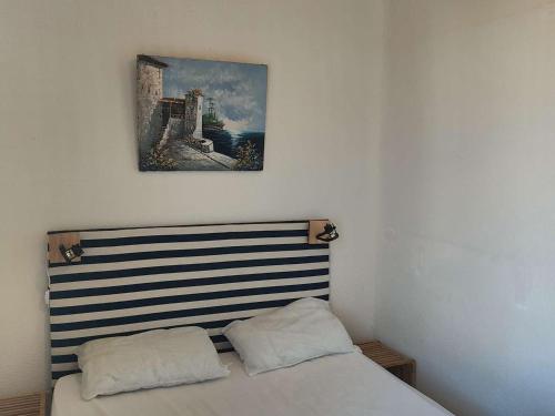 un lit dans une chambre avec un tableau sur le mur dans l'établissement Appartement T2 avec Mezzanine, Piscine et Parking à 1.5 km des plages - FR-1-195-110, au Barcarès