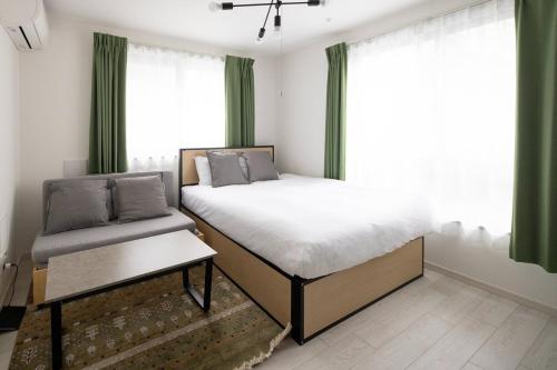 a bedroom with a bed and a window with green curtains at aLATO Omorimachi in Tokyo