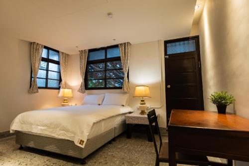 um quarto com uma cama, uma secretária e 2 janelas em 文坊 Wen Guest House em Taipei