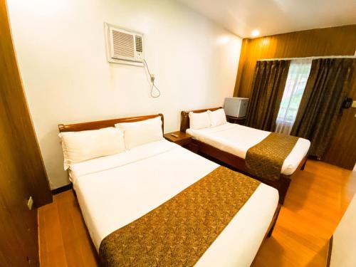a hotel room with two beds and a window at Hortz Hotels And Resorts in Tagaytay