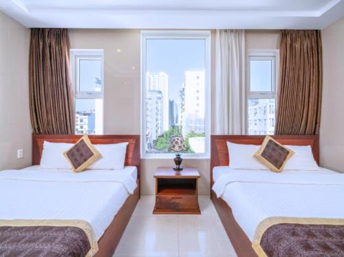 ダナンにあるDubai Hotelのベッド2台と窓が備わるホテルルームです。