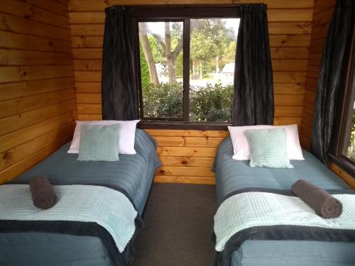 two twin beds in a room with a window at South Brighton Holiday Park in Christchurch