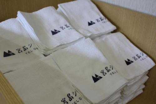 a pile of white towels with asian writing on them at Miyajima Seaside Hotel in Miyajima